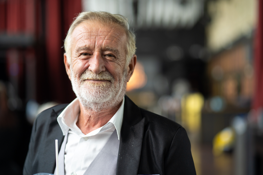 Older man in a business suit, looking straight ahead.