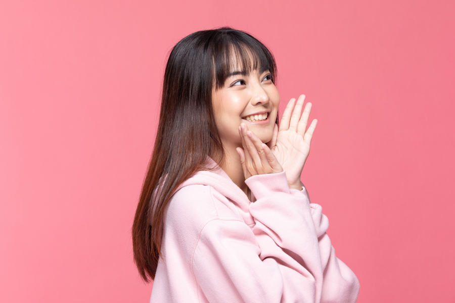 Young woman posing for a picture with her hands under her chin.