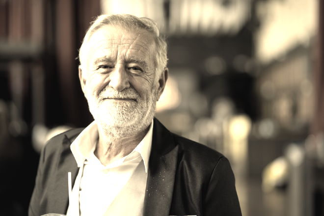 Older man in a business suit, looking straight ahead.