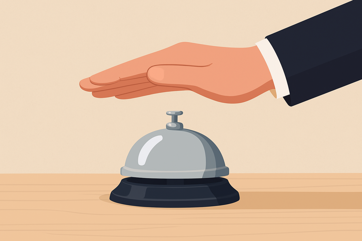 Hand hovering over a silver service bell on a desk, symbolizing a moment of decision at the point of entry into a service system.