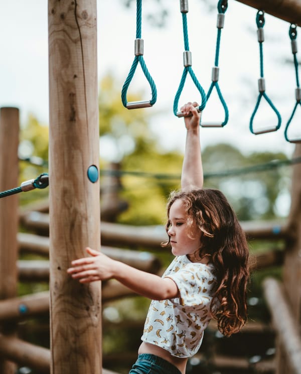 A girl swinging on monkey bars.